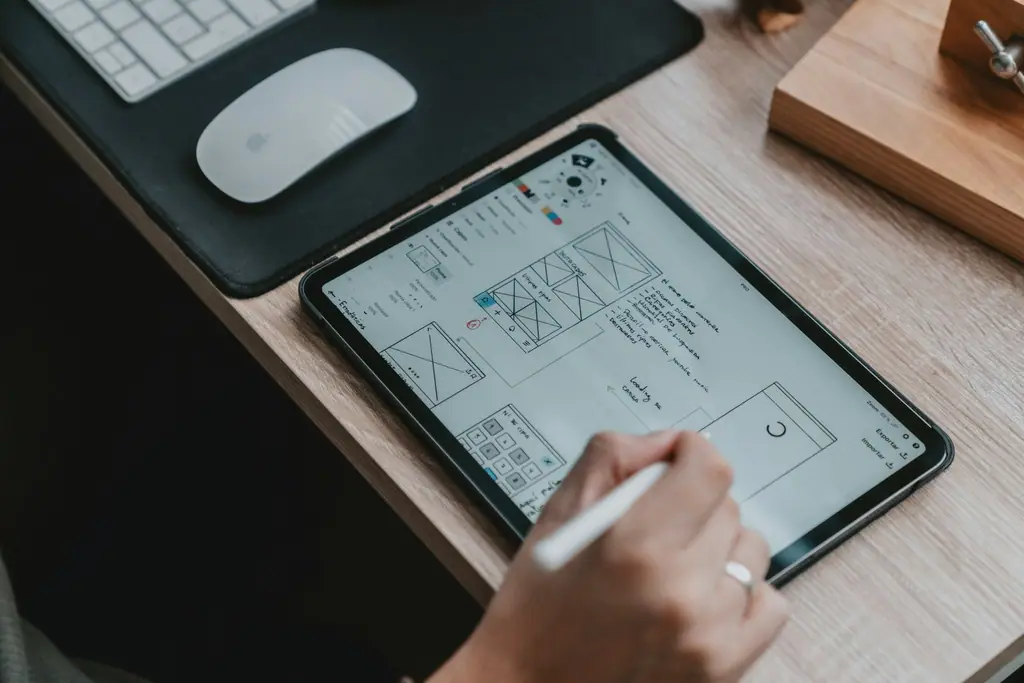 Designer sketching a UI and UX wireframe on a tablet with a stylus